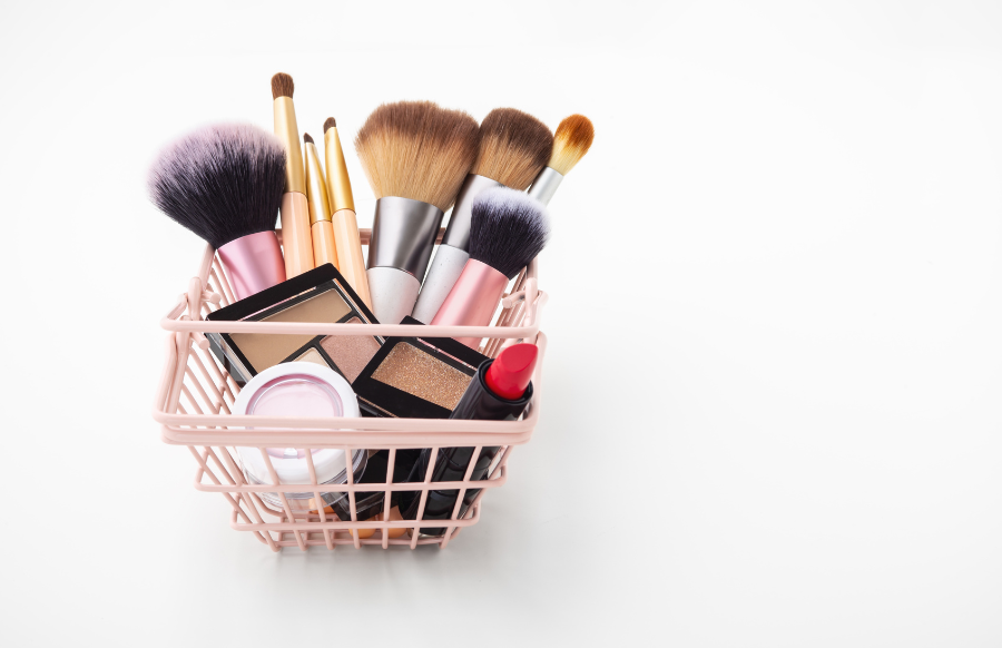 makeup cosmetic products in shopping basket on white background