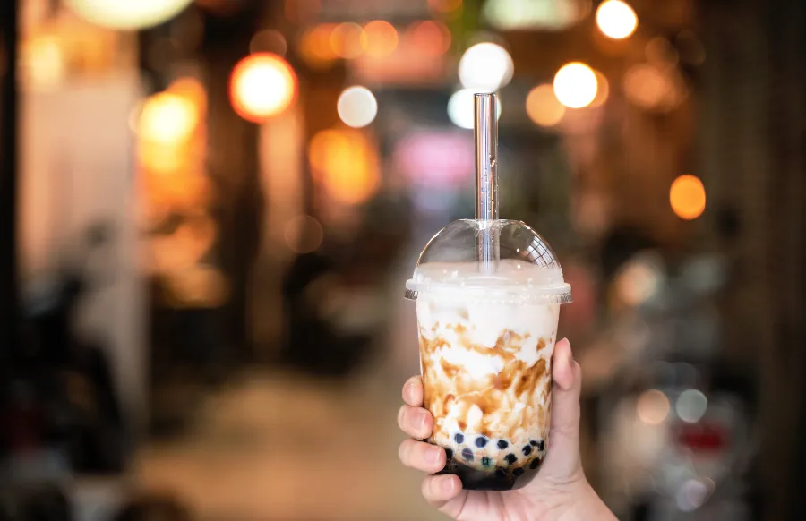 a shot of brown sugar flavored tapioca pearl bubble milk tea with glass straw in night market of Taiwan