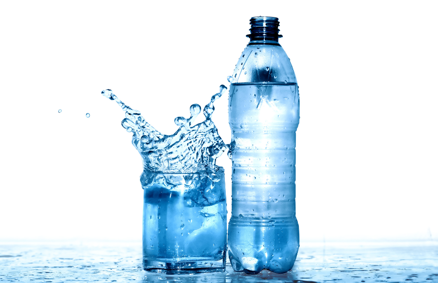 Glass of splashing water near plastics bottle