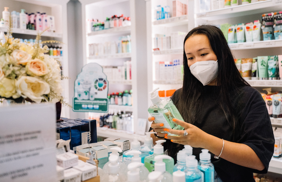 woman in black shirt and face mask holding an alcohol in a pharmacy