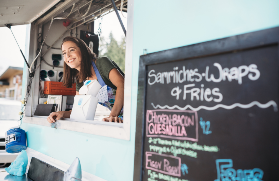 a young woman smiling at the window of her food truck